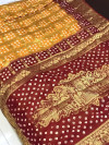 Yellow and maroon color pure hand bandhej silk saree with zari weaving work